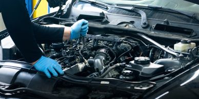 Mechanic inspecting a car engine with gloves on.