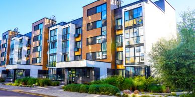 Modern apartment complex with glass and wooden panels.