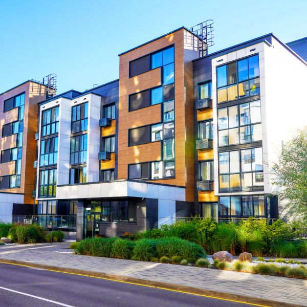 Modern apartment building with glass balconies and landscaped greenery.