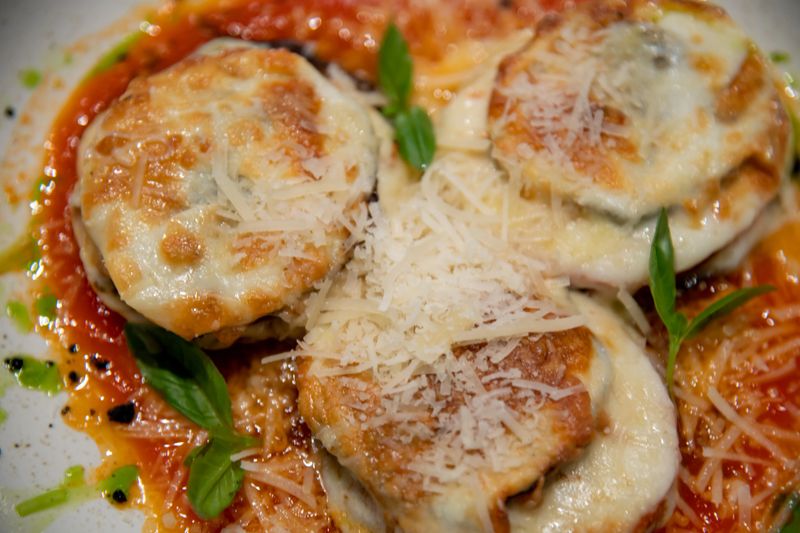 Plates are adorned with a delectable pasta dish that includes herbs and grated cheese. The warm atmosphere of the cafe invites diners to savor this culinary creation.