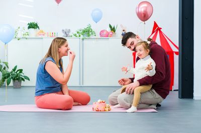 A family celebrating a child's birthday with cake and balloons indoors.
