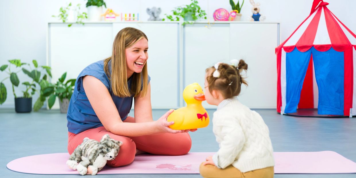 Woman and child playing with a yellow duck toy indoors.
