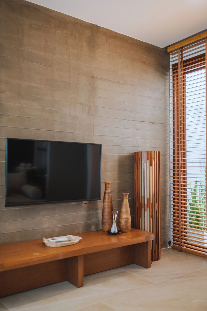A contemporary living room featuring a flat-screen TV mounted on a wooden-paneled wall with decorative vases and a sleek entertainment console.