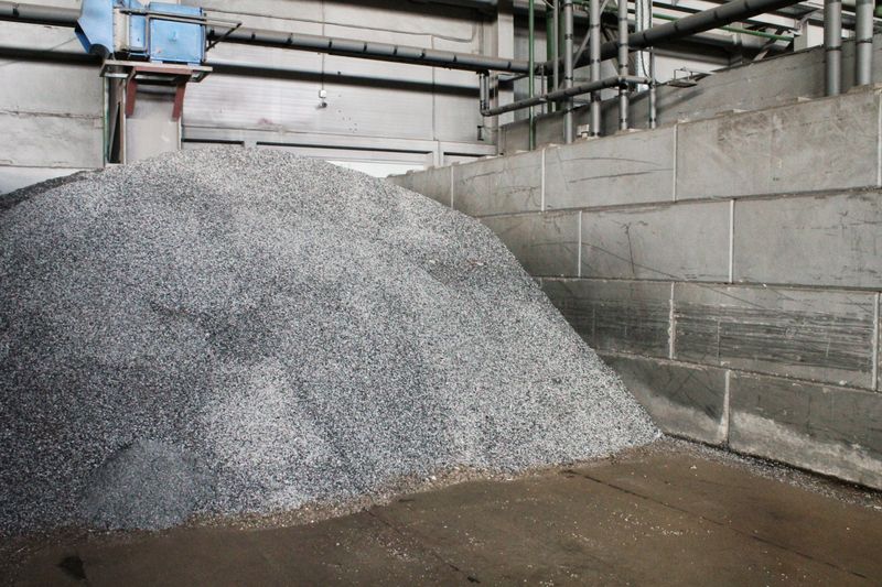 Pile of metal shavings in industrial setting. Large heap of metal chips on floor. Plant scene with metal shavings and walls. Scrap heap in factory environment. Storage of metal waste in workshop space