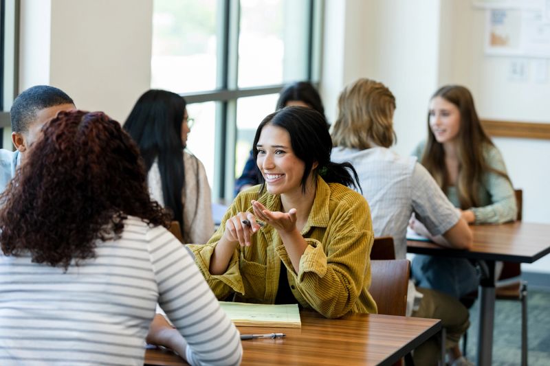 Multiracial group of students having a discussion in a classroom. Teamwork, collaboration, and communication.