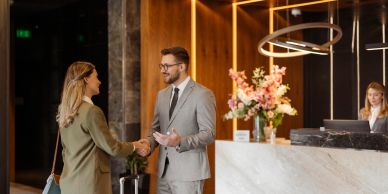Business professionals shaking hands in a modern hotel lobby.