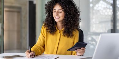 Young woman working with documents and calculator at office desk.