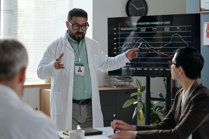 Waist up portrait of animated Middle Eastern doctor giving presentation and pointing at statistics data during medical conference copy space