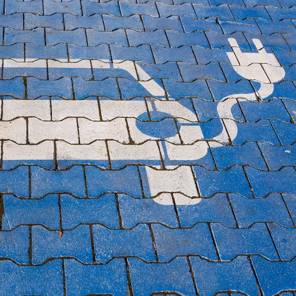 Electric vehicle charging station symbol on pavement.