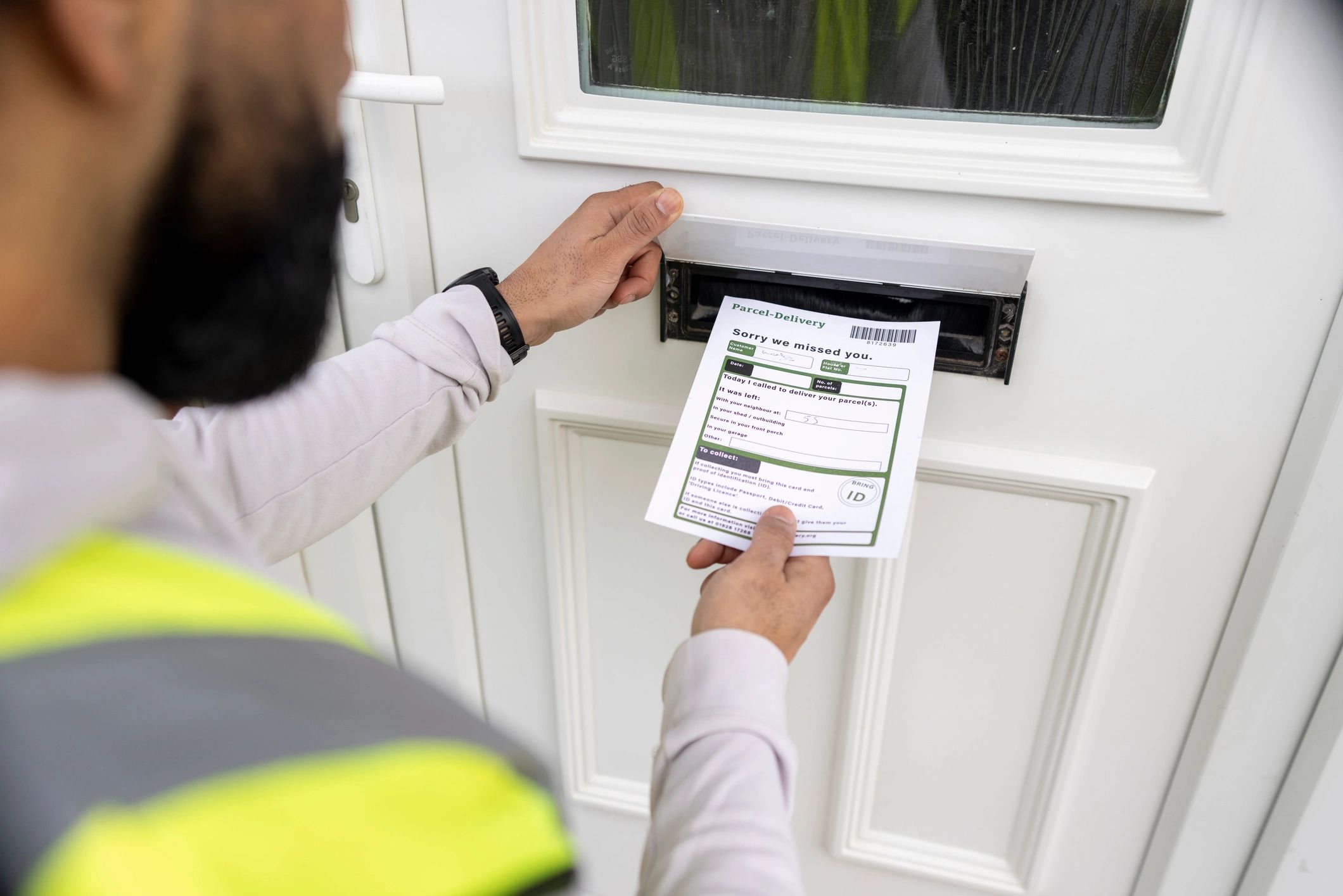 Man inserting a delivery notice into a door flap.