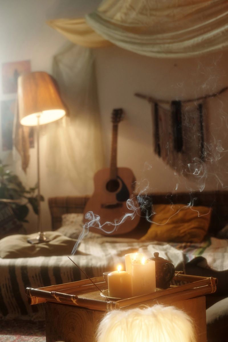 Warm and inviting lounging space with a glowing candle on wooden table, soft lamp light, and acoustic guitar in the background creating relaxed atmosphere