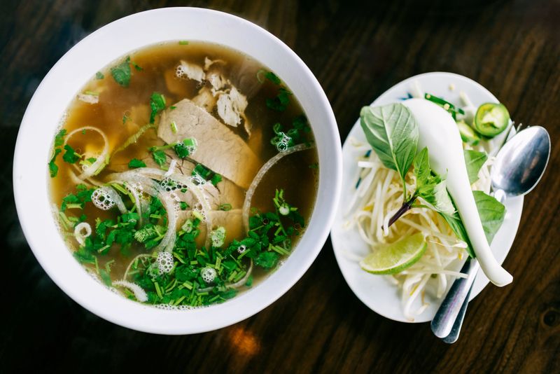 Delicious warm Pho noodle soup, a soothing hot beef broth with rice noodles, beef,  and fresh vegetables like cilantro, Thai basil, and bean sprouts.