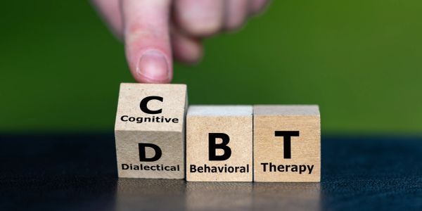 Wooden blocks spelling out CBT with a finger pointing on them.