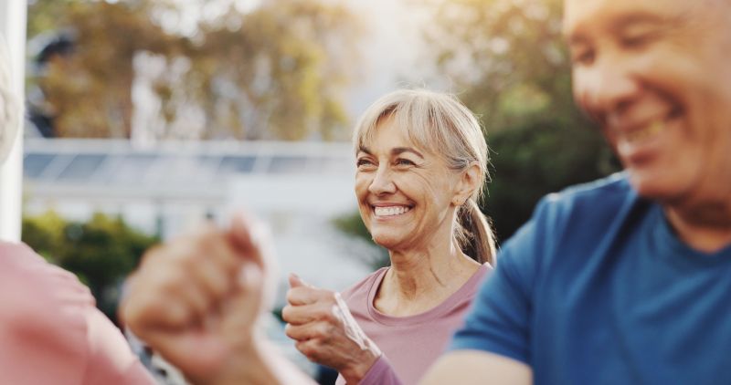 Senior woman, exercise and group in garden at retirement village, health and fitness class in morning. Elderly people, workout and diversity with cardio training, excited and wellness in summer