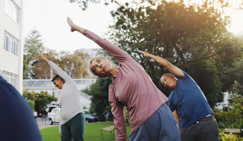 Fitness, elderly people and outdoor with stretching for yoga, 
exercise class or wellness in retirement. Senior group, pilates session or warm up in garden for balance, breathing control or community