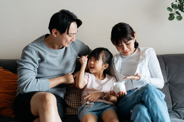 Family saving money together with a piggy bank.