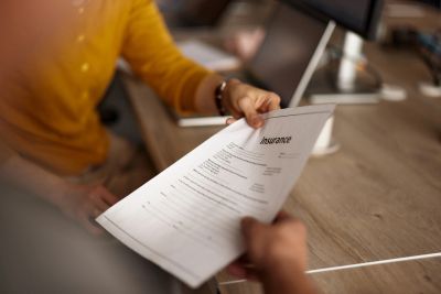 A person holding an insurance document in an office.
