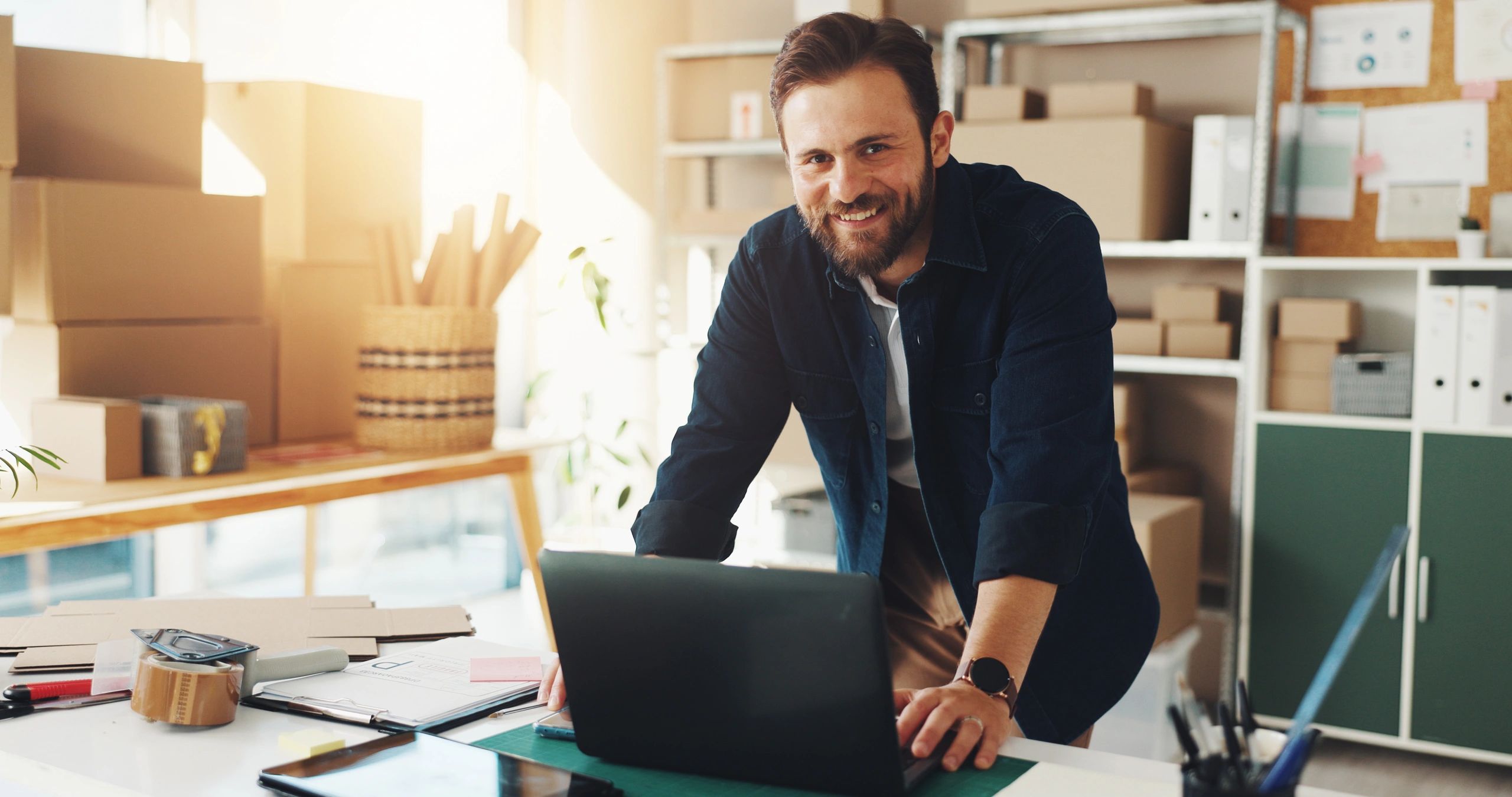 Small business owner smiling while reviewing AI-powered reporting on a laptop in his workspace