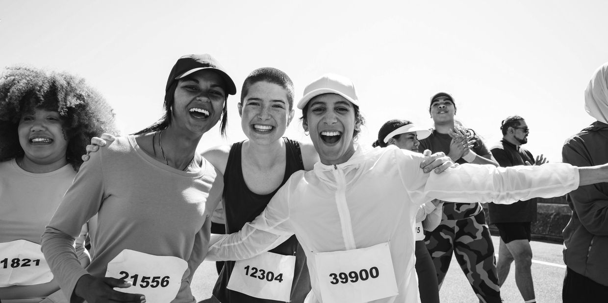 Group of runners celebrating together after a race with their race numbers and running gear