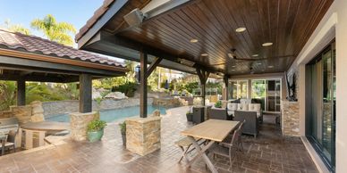 Spacious covered patio with seating and a pool in the background.