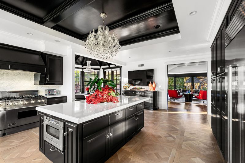 An elegant kitchen with modern decor, large windows, crystal chandelier, and artistic accents in a luxury home