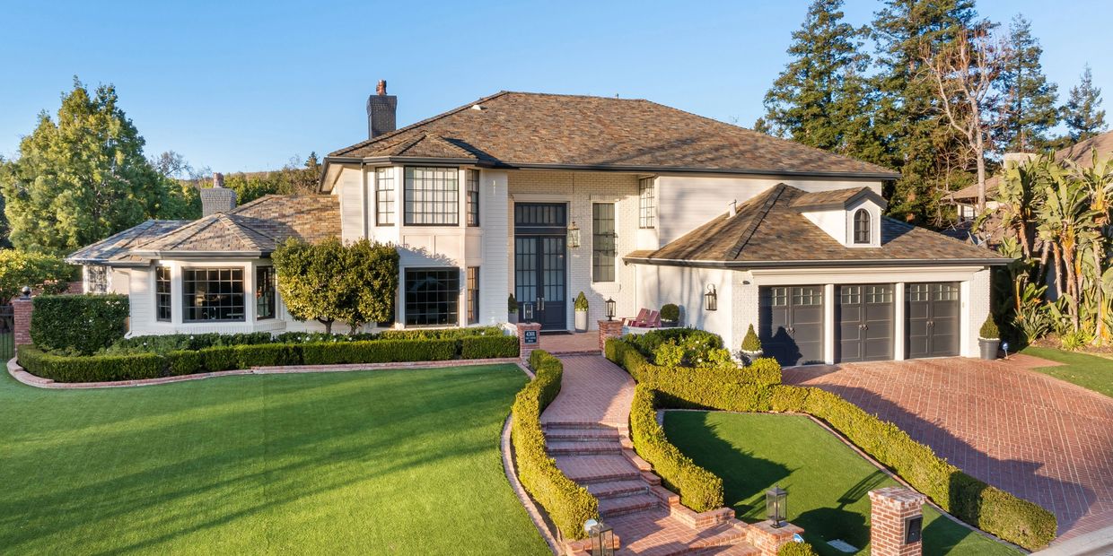 Luxury Newport Beach home with manicured lawn, flower beds, and palm trees maintained by OC Landscap
