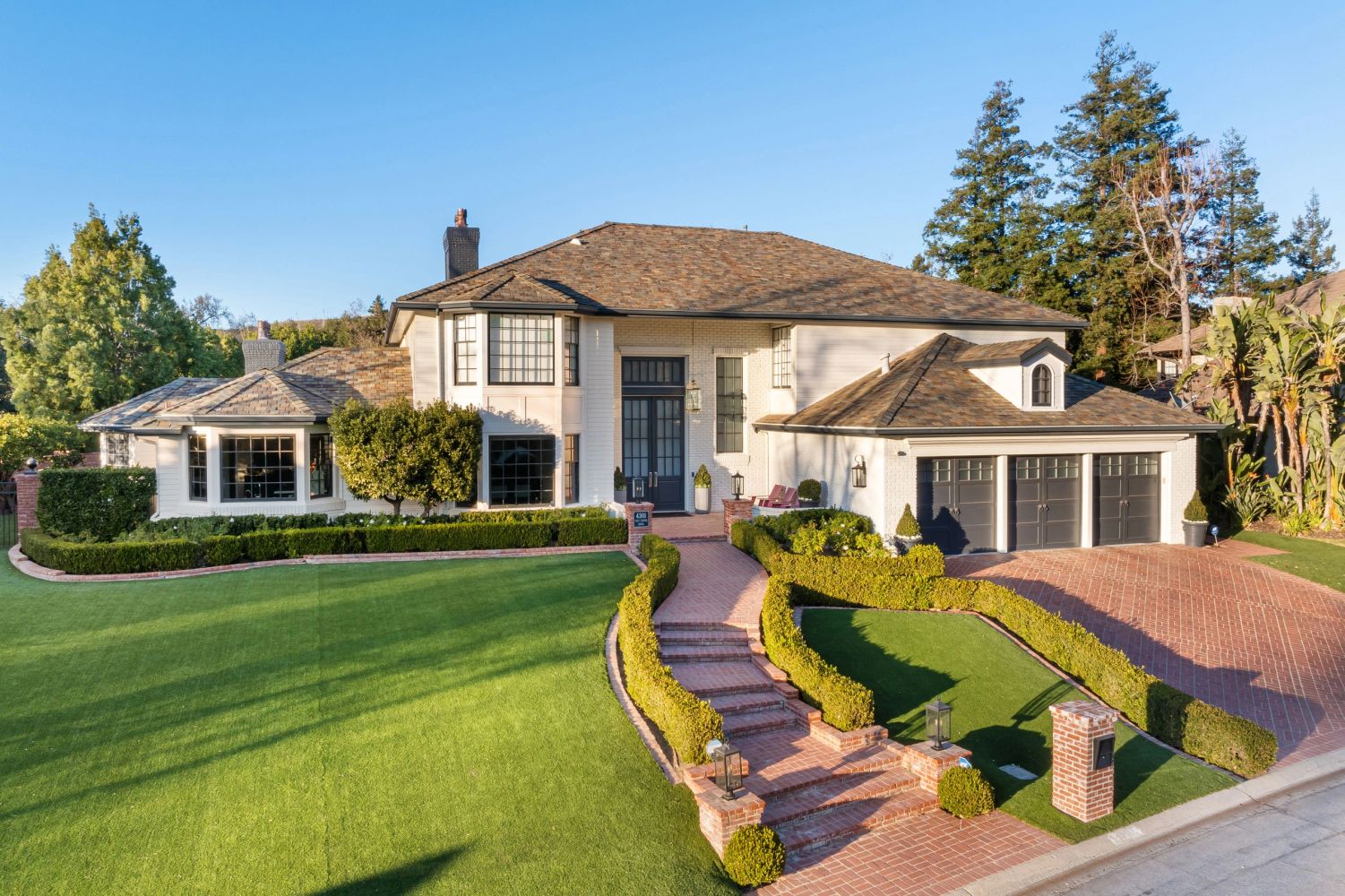 Elegant two-story house with manicured lawn and brick driveway.
