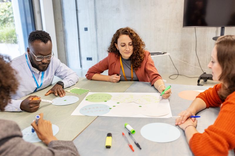 Diverse businesspeople sitting at table working together on various seminar activities. Highlights inclusivity, professional collaboration, and dynamic learning at a convention center.