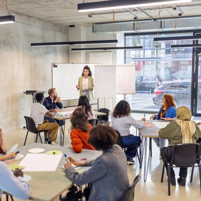 A woman leads a workshop with diverse participants in a modern room.