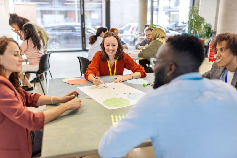 Multiracial businesspeople seated in small groups, participating in diverse activities during a seminar. Diverse group of professionals working on activities during a seminar.