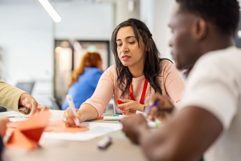 Businesswoman helping a group with seminar tasks at a convention center reflecting her commitment to promoting collaborative and engaging learning experiences.