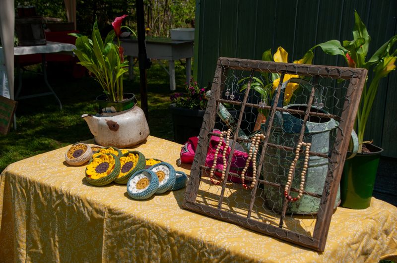 A charming collection of handmade crafts and potted plants aesthetically arranged on a decorated table at an outdoor fair, showcasing creativity, sustainability, and rural artistry.