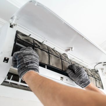 Person cleaning a dusty air conditioner filter wearing gloves.