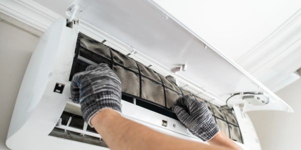 Person cleaning an air conditioner's filter with gloves.