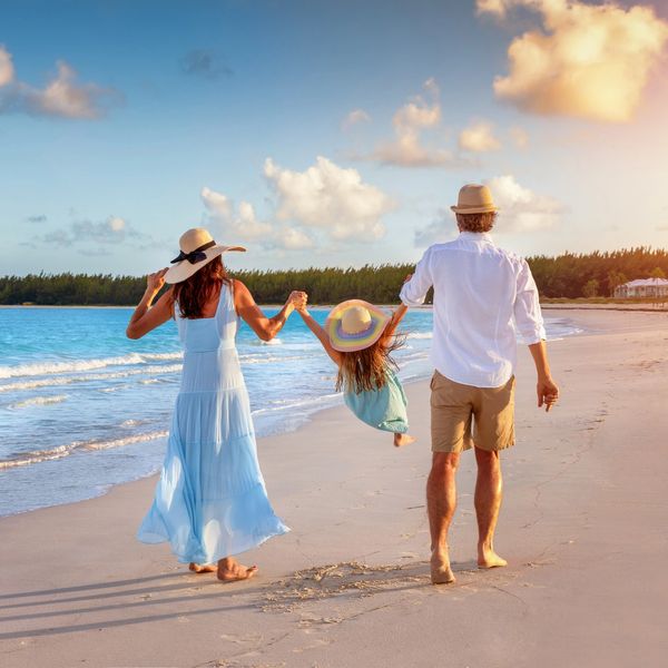 Family enjoying a playful walk on the beach at sunset.