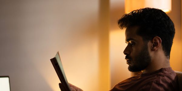 A man reading a book in soft, warm lighting.