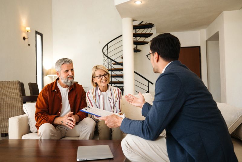 Smiling mature couple talking with financial advisor at home