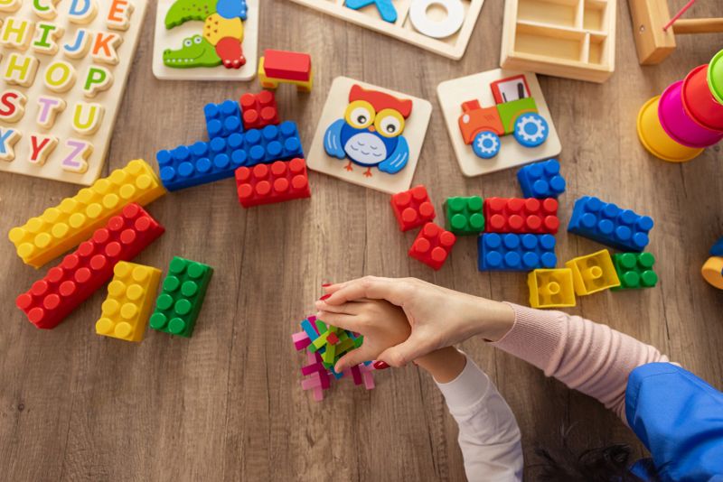 A nurse and an autistic boy engage in memory-building activities using colorful sensory toys.
