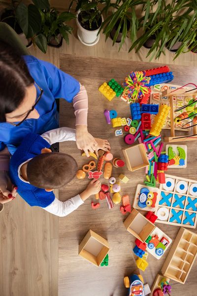 Adult and child playing with educational toys on a table.