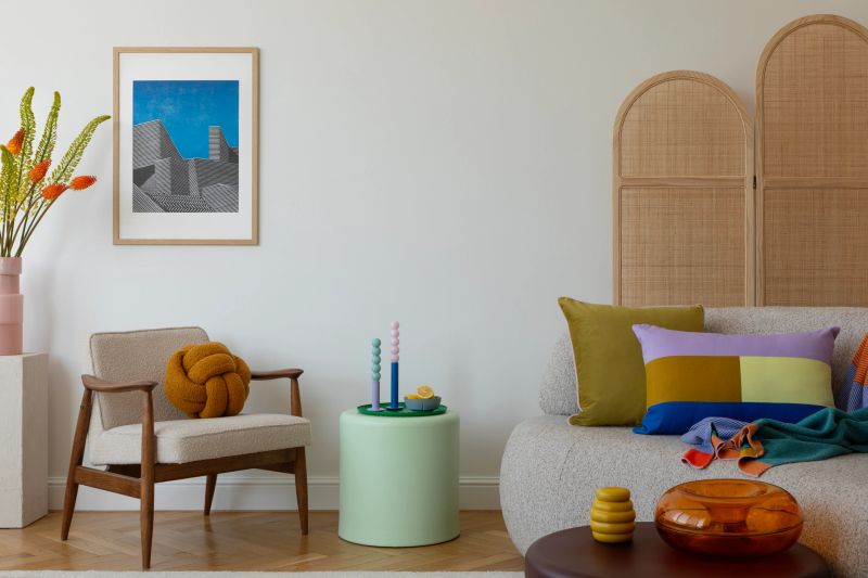 Stylish living room with a mid-century modern chair, colorful pillows, and a unique knot cushion, creating a cozy and contemporary space. Mock up poster.