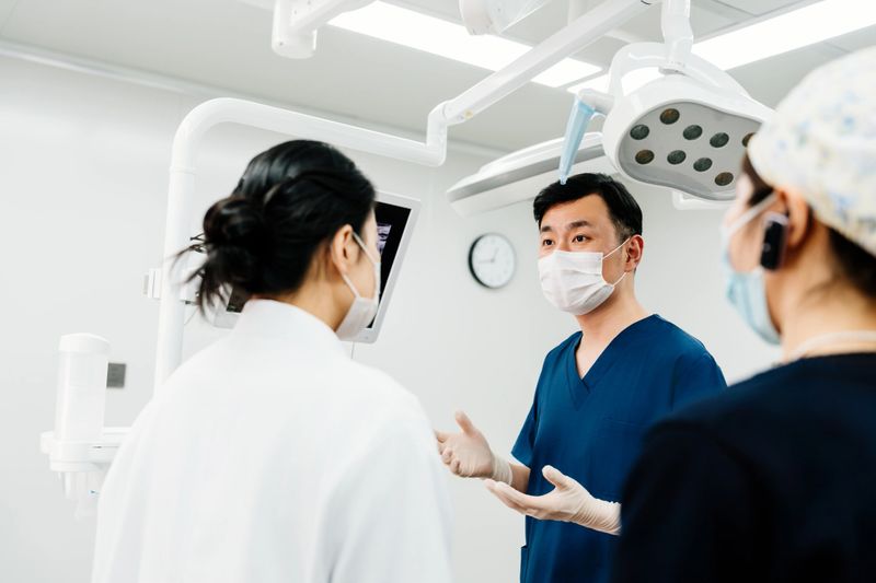Asian male doctor talking with female doctor about the x-ray image in the operating room.