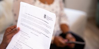 Person holding a U.S. naturalization test study sheet with another person in the background.