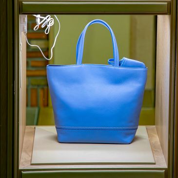 Blue handbag displayed on a stand.