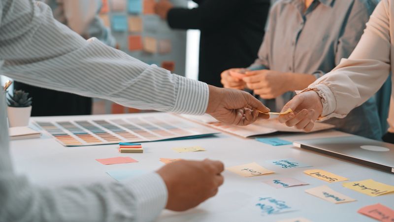 Collaborative brainstorming session with sticky notes and color palettes showcasing team interaction and creative planning in a modern workspace environment SACTR