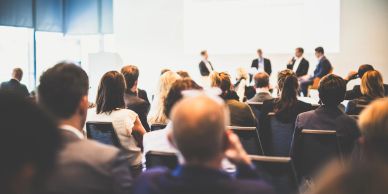 Audience attentively listening to a panel discussion in a conference room.