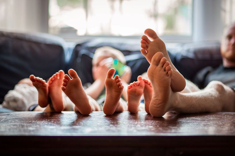 A family hangs out on their couch with feet up in the coffee table