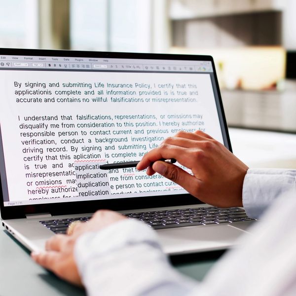 Person reviewing and editing a life insurance policy document on a laptop.