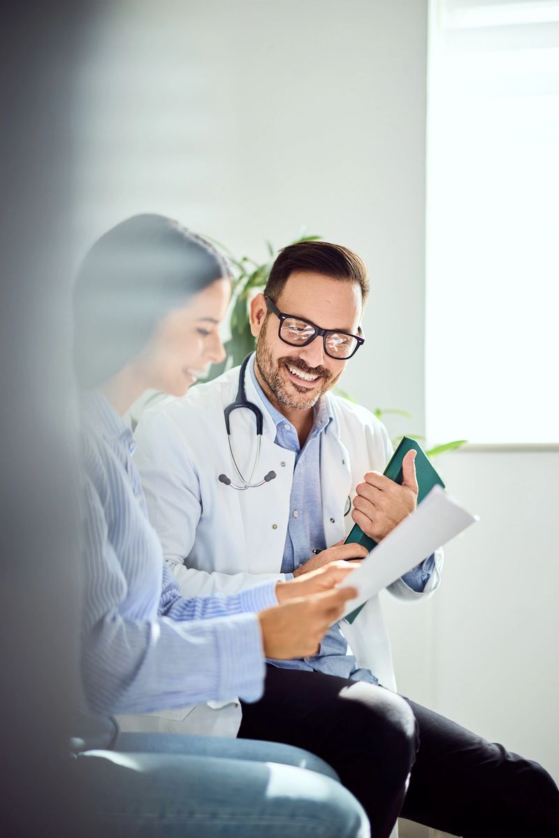 A doctor and a patient smiling while reviewing medical documents in a clinical office, emphasizing professionalism and trust in healthcare.