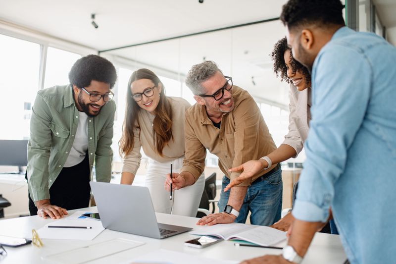 Smiling corporate professionals in a business meeting, engaged in teamwork and strategic planning. A diverse team discussing project ideas, analyzing data, and working together for success in a office