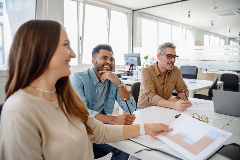 A close-up of diverse professionals engaged in a dynamic brainstorming session, exchanging ideas, analyzing data, and making strategic business decisions in a modern corporate office.